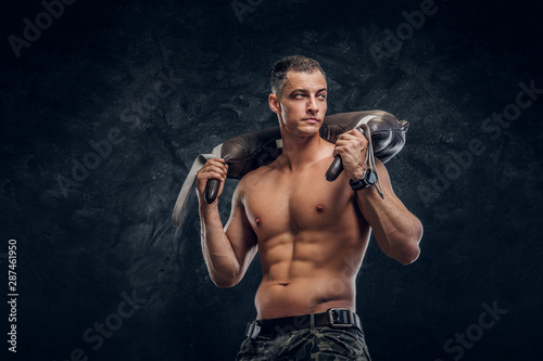 Muscular attractive hot man is holding weight bag while posing for photographer.