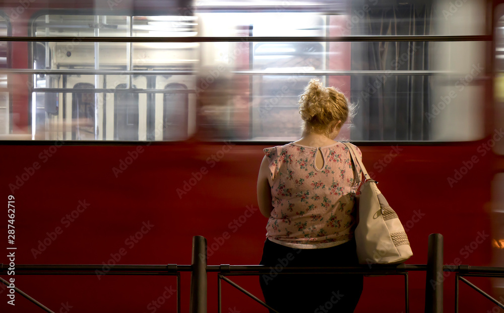 One young blond woman standing alone at a bus stop in the night