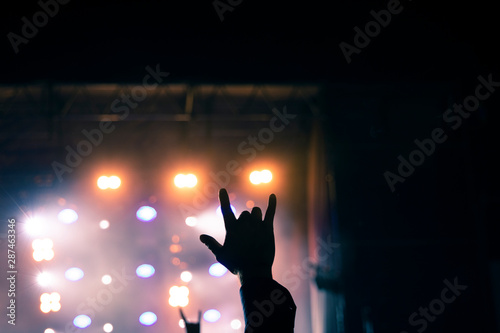 wonderful rock music atmosphere performance picture with hand up on festival stage projector colorful illumination background in night time 