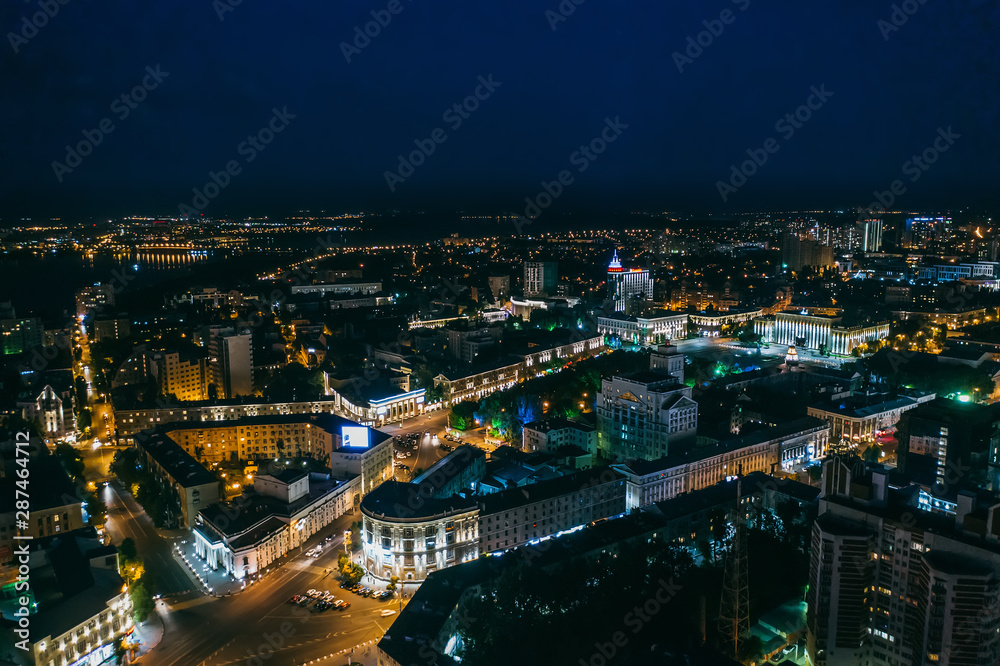 Night city aerial view, flying above high illuminated modern glass building with reflections in Europe town midtown
