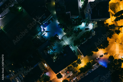 Aerial top down view of night city buildings and illuminated roads, drone photo