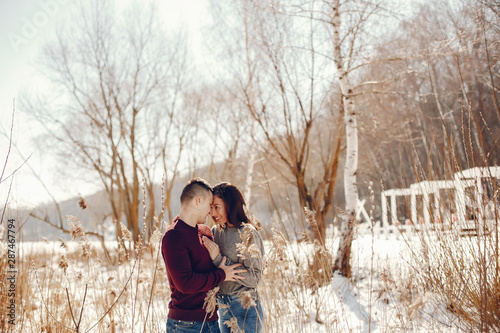 Cute couple have fun. Boy and girl in a winter park. Man in a red sweater. Brunette in a gray sweater © hetmanstock2