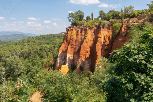 Ochre Trail in Roussillon, Hiking path in orange ocher cliffs surrounded by green forest in Provence, Southern France