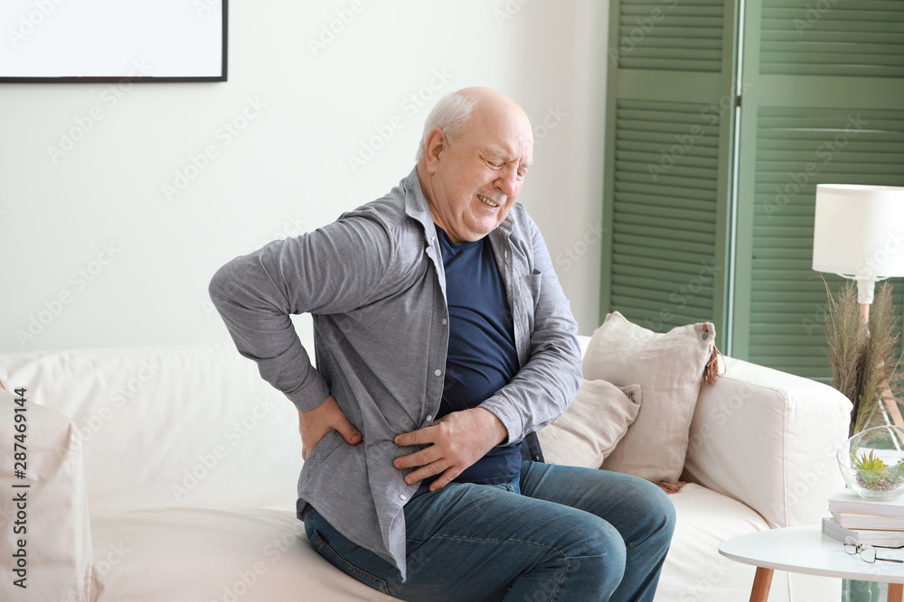 Senior man suffering from back pain at home Senior man suffering from back pain at home