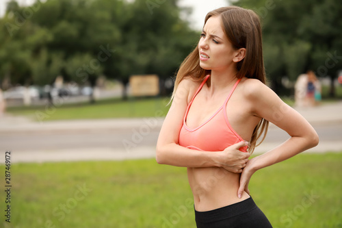 Young sporty woman suffering from pain in back outdoors © Pixel-Shot