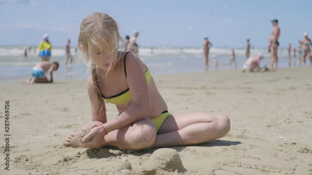 Little girl playing with sand on beach. Enjoying a lovely vacation. Little girl playing with sand on beach. Enjoying a lovely vacation.