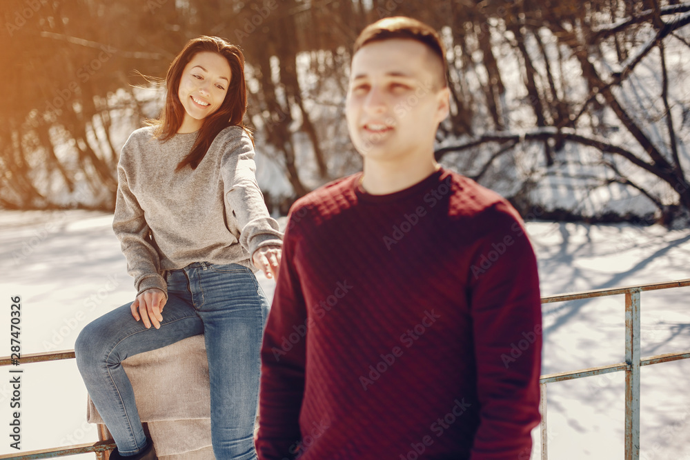 Cute couple have fun. Boy and girl in a winter park. Man in a red sweater. Brunette in a gray sweater