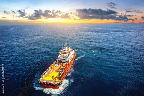 Supply vessel transport cargo for rig platform offshore at sunset.