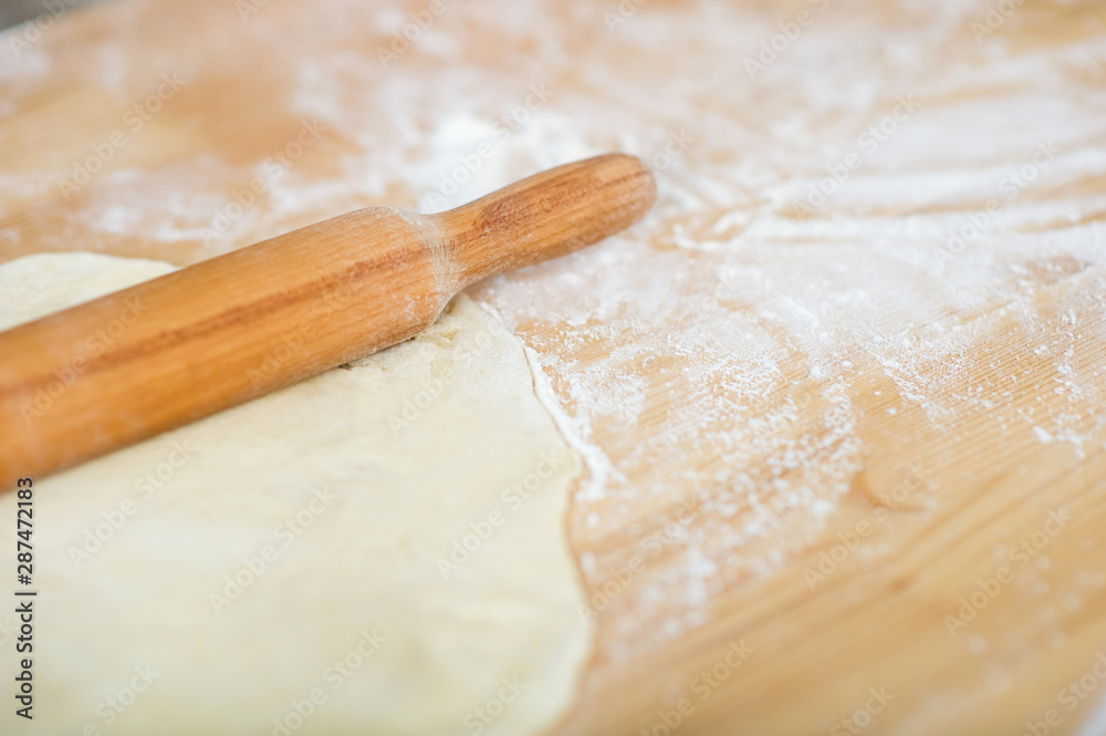 rolling pin and dough lie on a table sprinkled with flour rolling pin and dough lie on a table sprinkled with flour