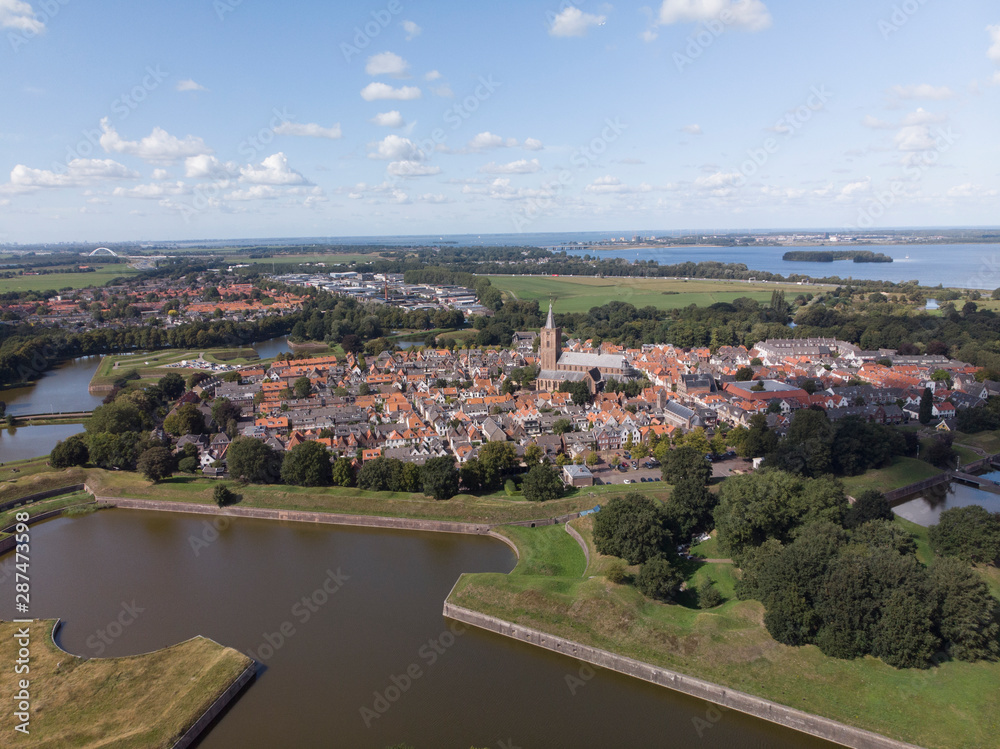 Aerial view on the fortification city Naarden Vesting with its defensive constructions surrounding the village against a blue sky with clouds