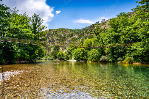 Tiny wooden and cable bridge above crystal clear water in river Neretva in village Ladanica  Bosnia and Herzegovina