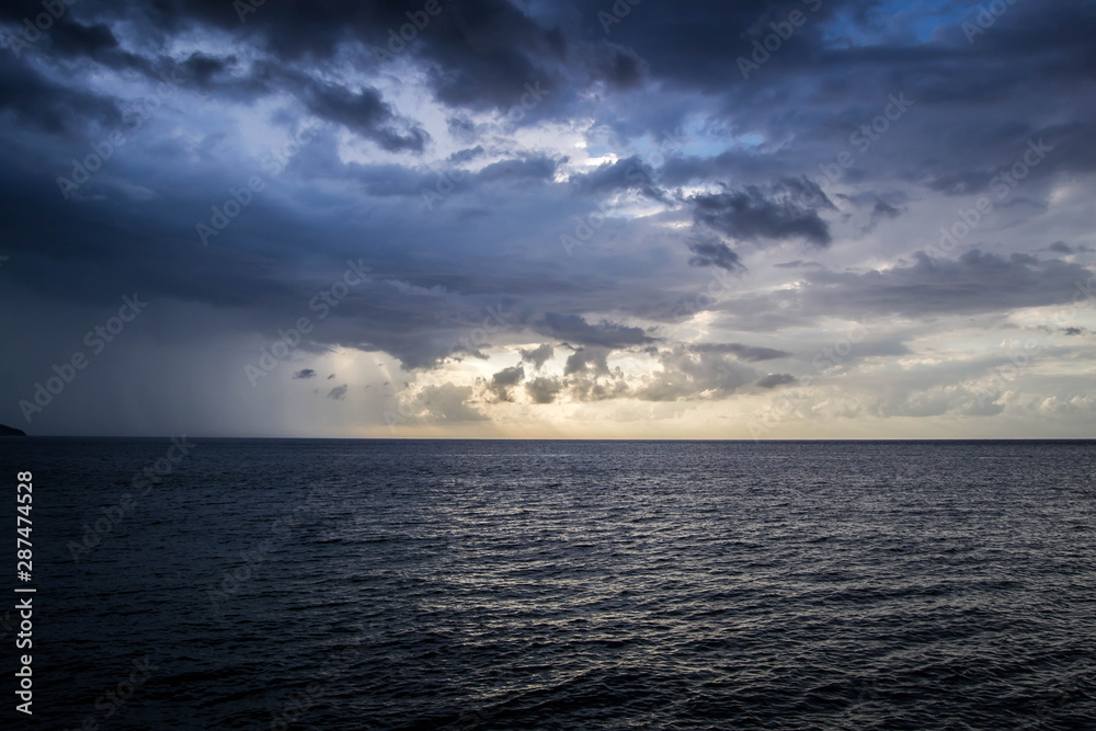 Sunset rays shining through the clouds over the ocean Sunset rays shining through the clouds over the ocean