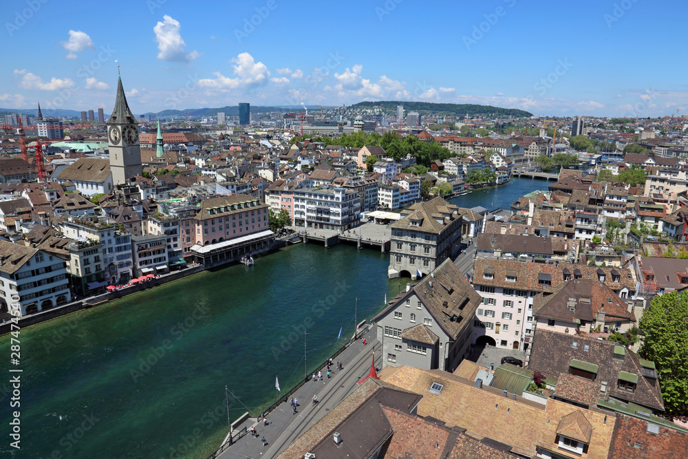 The Limmat river with The Church of St. Peter and it's large clock tower in the background, running through Zurich, Switzerland.