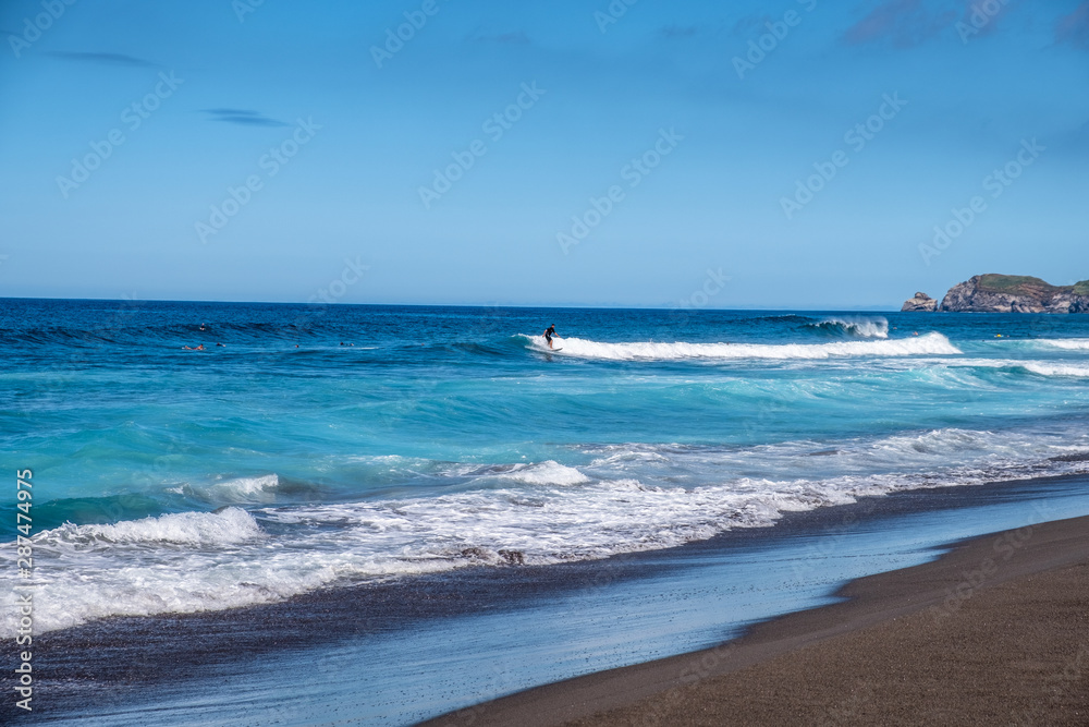 Beautiful landscape surfers riding a wave on Santa Barbara Beach, Black Sand Beach, Ribeira Grande, Sao Miguel Island, Azores, Portugal