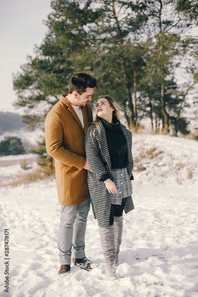 Fototapeta premium happy young couple walking through the park on a snowy day