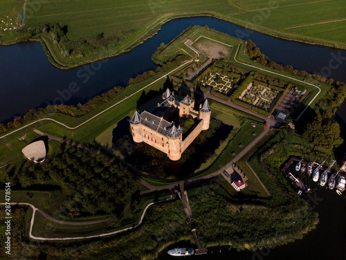 Aerial view of the Muiderslot castle in Muiden near Amsterdam and its lush gardens with surrounding water entrenchment in the late afternoon sun photo