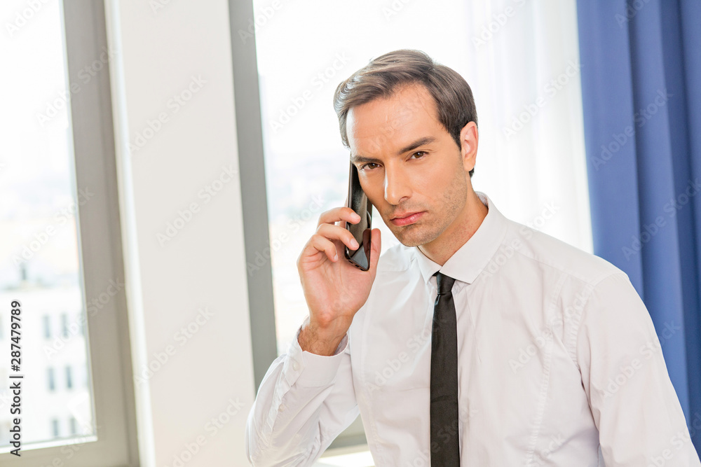 Businessman talking on the mobile phone in his hotel room Businessman talking on the mobile phone in his hotel room