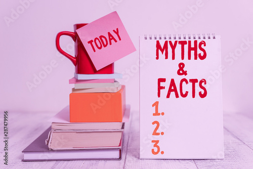 Word writing text Myths And Facts. Business photo showcasing usually traditional story of ostensibly historical events Cup sticky note stacked note pads books square box spiral wooden table