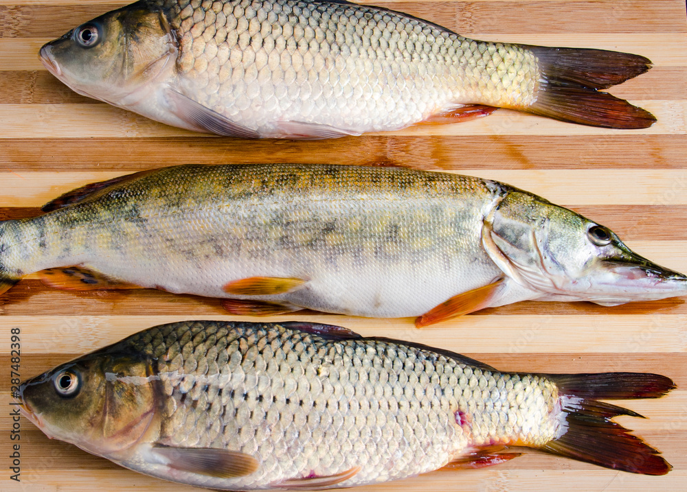 Uncooked fish on cutting board in meal preparation concept Uncooked fish on cutting board in meal preparation concept