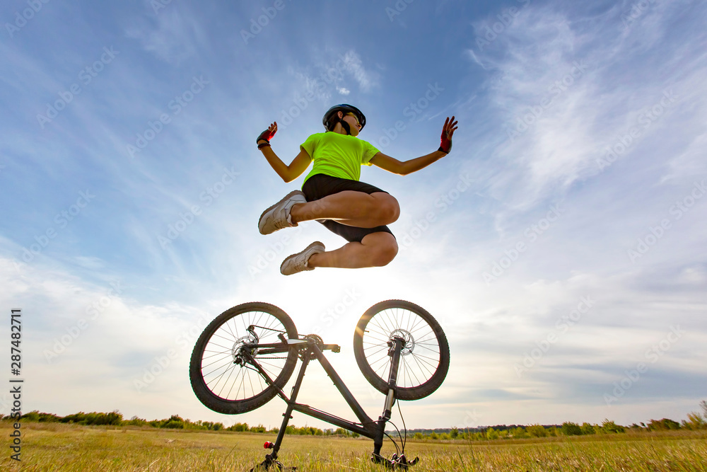 girl cyclist jumps into the sky on the background of the bike. girl cyclist jumps into the sky on the background of the bike.