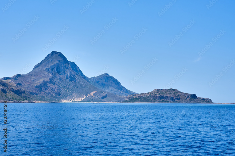 Rocky islands near Crete, Greece, with clear sky on a background and blue sea on a foreground. Copy space. Rocky islands near Crete, Greece, with clear sky on a background and blue sea on a foreground. Copy space.