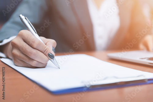Close up hand of woman holding pen thinking and writing data or business planning in paper for remember and learn,Writing Education Concept