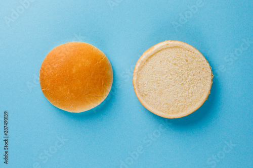 Burger bun empty isolated. American food classic round burger bread isolated on a blue background. Grilled burger bun top. photo