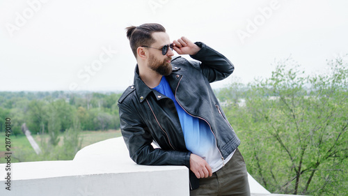 Side view fashion portrait of thinking stylish young handsome bearded hipster man in sunglasses looking away.