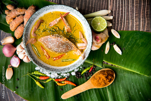 Crab meat coconut milk curry, in bowl and ingredient of Thai Red curry paste on brown wooden background Thai food / Select focus imageand top view image, thai food concept. photo