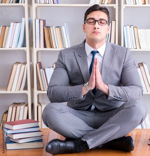 Businessman student in lotus position concentrating in the libr photo