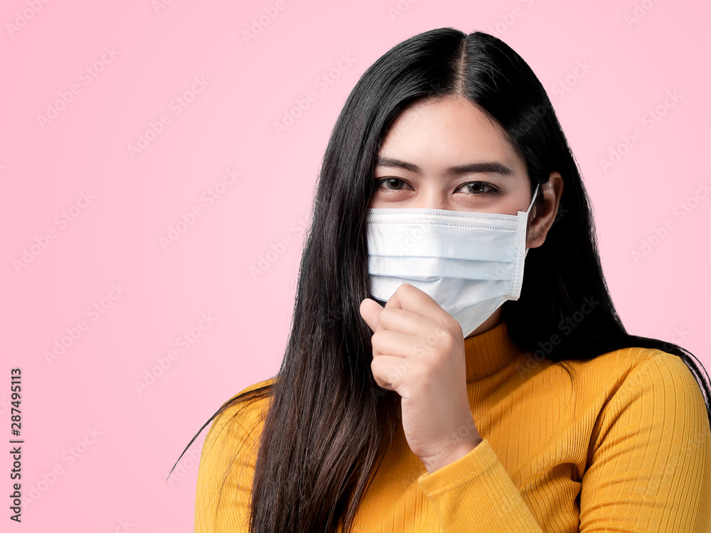 Asian woman wearing yellow sweater and coughing with mask on pink background. Asian woman wearing yellow sweater and coughing with mask on pink background.
