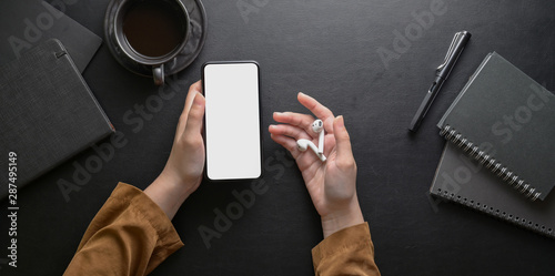 Female hand holding smartphone on dark stylish workplace photo