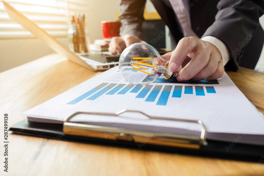 Businessmen who use a laptop and have a light bulb put on the tablet concept with innovation and creativity in office. Businessmen who use a laptop and have a light bulb put on the tablet concept with innovation and creativity in office.