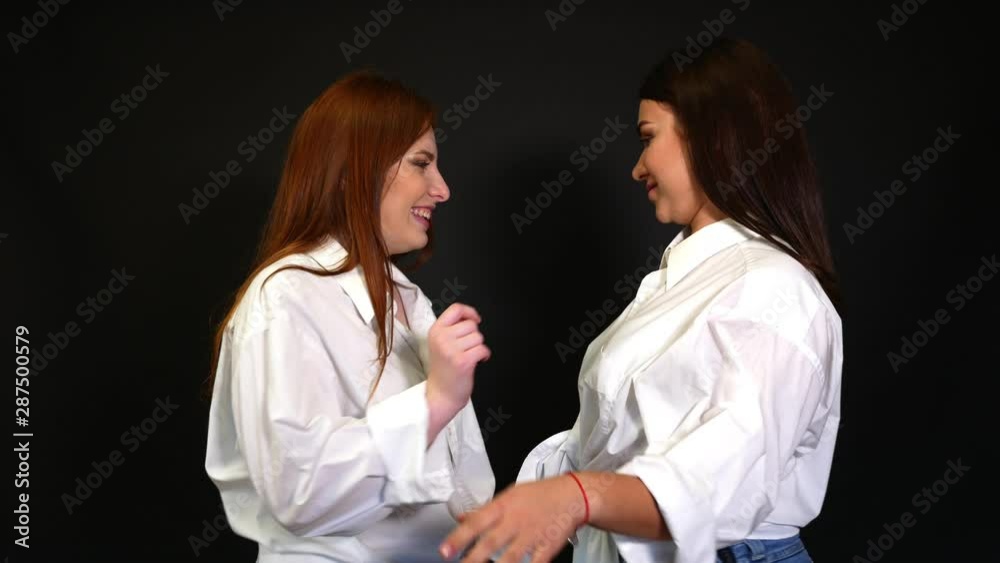 Girls in white shirts dancing and fooling around on a black background Girls in white shirts dancing and fooling around on a black background