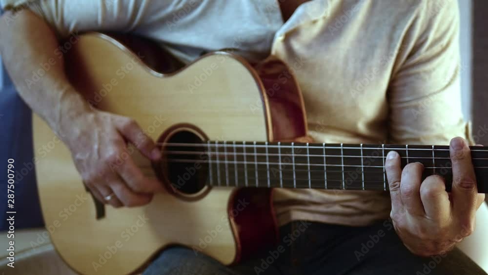 Musician is playing acoustic guitar. Fingers with golden ring touching