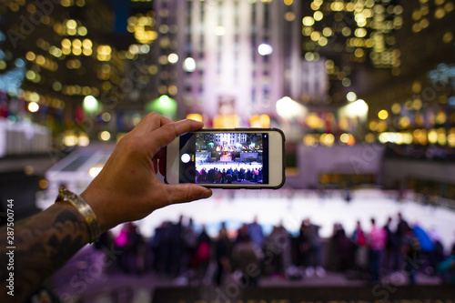 A tourist is taking pictures with his phone at the Rockefeller tower in New York, USA. Rockefeller Plaza is an American Art Deco skyscraper.