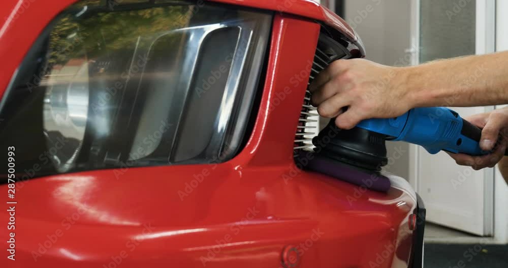Worker polish a car with auto polisher. Close up of worker hands using an auto polisher to polish the car body in the workshop Worker polish a car with auto polisher. Close up of worker hands using an auto polisher to polish the car body in the workshop