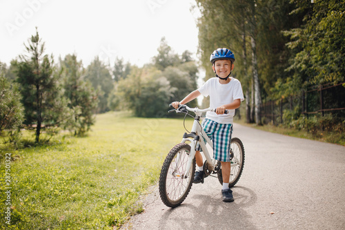 Fototapeta Naklejka Na Ścianę i Meble -  Little boy in helmet learning to ride bicycle park having fun.