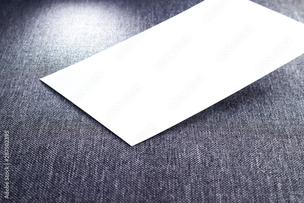 Blank paper, white empty business card, poster or flyer on gray fabric texture. Blank signboard with copy space area for text or slogan Blank paper, white empty business card, poster or flyer on gray fabric texture. Blank signboard with copy space area for text or slogan
