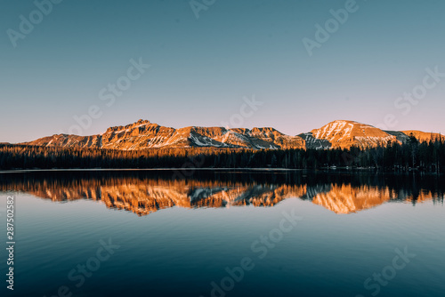 Snowy mountains reflecting in Mirror Lake, in the Uinta Mountains, Utah photo
