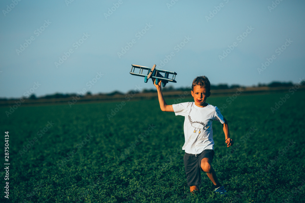Fototapeta premium cute boy playing with toy airplane outdoor in meadow