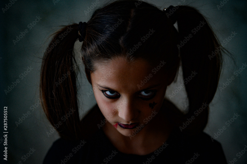 young little caucasian girl with pigtails with dark gothic makeup looking angry during Halloween holiday party looks like movie character young little caucasian girl with pigtails with dark gothic makeup looking angry during Halloween holiday party looks like movie character