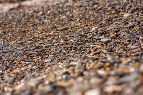 Sea pebble - beautiful gravel beach in sunlight, blurred background