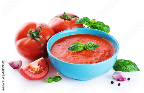 Bowl of tomato soup, tomatoes, garlic and basil  isolated on a white background.