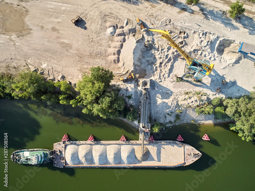 Photography Crane is loading sand and gravel onto barge ship for river transport