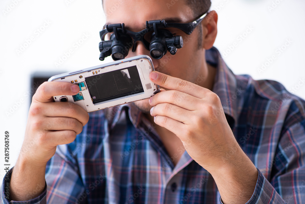Young handsome technician repairing mobile phone Young handsome technician repairing mobile phone