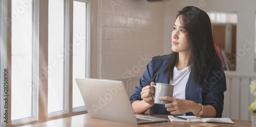Professional female freelancer having coffee break while working on her project