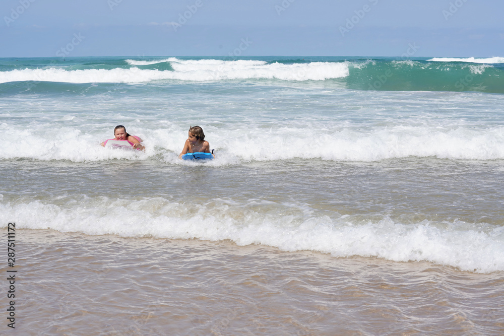 Kids riding bodyboards in ocean waves