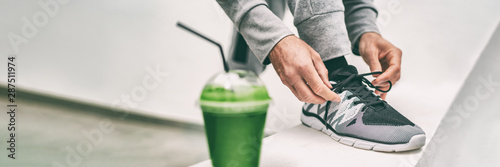 Green juice weight loss smoothie fit man getting ready for cardio run workout tying running shoes laces drinking detox drink panoramic banner. Fitness runner athlete with healthy vegan juice.
