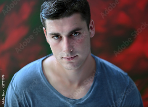 Close-up portrait of a handsome young man with black hair on a colorful background.